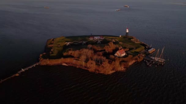 Aerial view of Vuurtoren eiland amsterdam The Netherlands drone shot nature small island in Holland a lighthouse and water surrounding it at sunset. — Stock Video