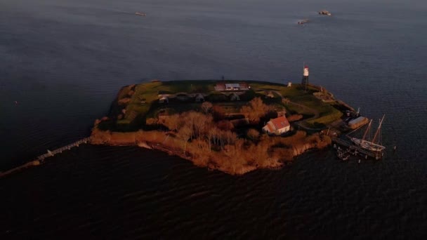 Aerial view of Vuurtoren eiland amsterdam The Netherlands drone shot nature small island in Holland a lighthouse and water surrounding it at sunset. — Stock Video