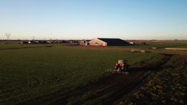 Tractor en una granja en un terreno de hierba al atardecer imágenes cinematográficas de drones aéreos. — Vídeos de Stock