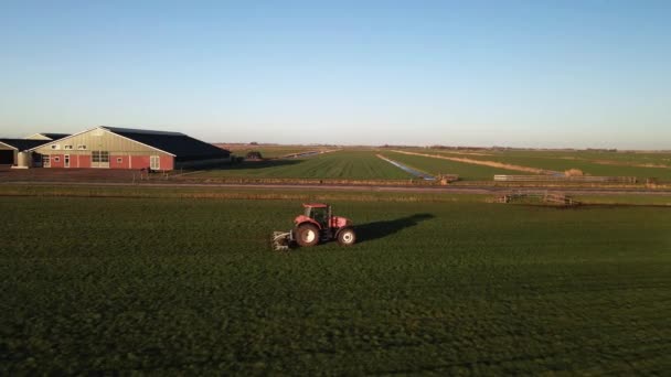 Traktor på en gård på en gräsmark vid solnedgången antenn drönare film. — Stockvideo
