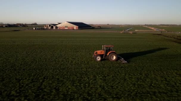 Tracteur dans une ferme sur une pelouse au coucher du soleil drone aérien séquences cinématographiques. — Video