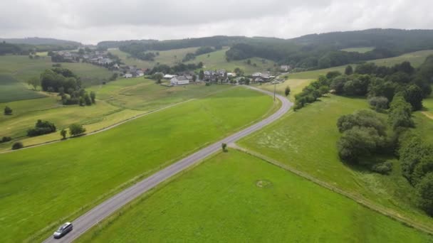 Duitse Eifel kronkelige weg door de heuvels in een zonnig grasland in de zomer. — Stockvideo