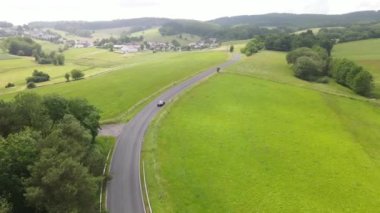 Alman Eifel yazın güneşli bir çayırda tepelerin arasından kıvrımlı bir yol..