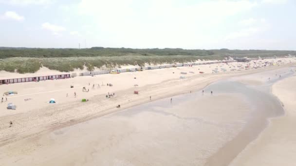 Widok z lotu ptaka na małe domy na plaży wzdłuż wybrzeża i wydmy w Oostkapelle, Zeeland, Holandia. — Wideo stockowe