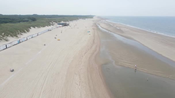 Widok z lotu ptaka na małe domy na plaży wzdłuż wybrzeża i wydmy w Oostkapelle, Zeeland, Holandia. — Wideo stockowe