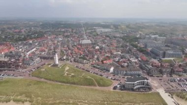 Egmond aan Zee, Hollanda 'da güneşli bir günde sahil şeridi. Sucu insanlar güneşte ve plajda dinleniyorlar..