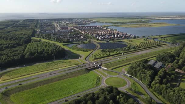 Moderní novátorská obytná čtvrť v Almere, podél vodní plochy, včetně solárního panelového pole. Nizozemsko, Flevoland. — Stock video