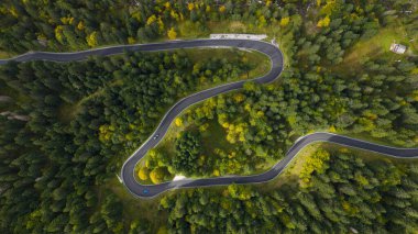 serpentine road, top down view. winding road that follows a curvy twisting path, mountainous forest area. Aerial top down photo.