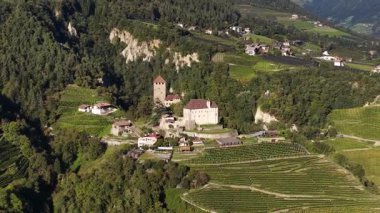 Tirol Kalesi, Tirol Kalesi tepesi Tirol İtalya. Elma bahçeleriyle çevrili. Kuzey İtalya. Hava aracı videosu.