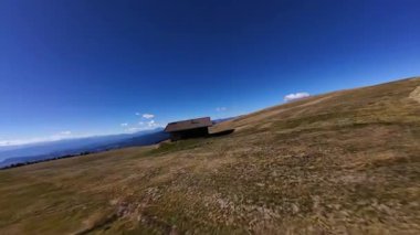 Dolomitler 'in dağlarındaki çayırların üzerinde ağaçtan yapılmış alp kabini. İtalya. Hava FPV videosu.