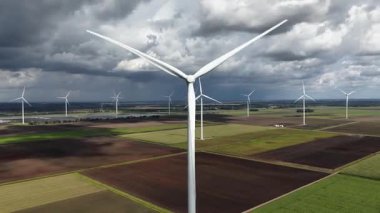Yel değirmeni, temiz ve yenilenebilir enerji üretimi. Çiftlik arazisi ve dramatik gökyüzü. Hava videosu.