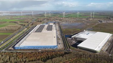 Aerial drone video capturing the large-scale construction site at Logistics Park Moerdijk, Netherlands, where some of Europes largest, modern distribution centers are being built. This highlights massive investment in infrastructure and global