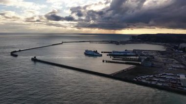 Dover, Kent County, İngiltere, 25 Ekim 2025: Dover Limanı 'nın gün batımında uluslararası feribotların iniş ve çıkışlarını gösteren bir hava aracı videosu. Deniz taşımacılığı, kamyonlar, arabalar ve sınır ötesi ticaretin hareketliliğini ön plana çıkarıyor.