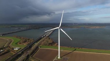 Moerdijk, Kuzey Brabant Eyaleti, Hollanda, 17 Kasım 2025: Rüzgar türbini ve Hollandsch Diep Yüksek Hız Köprüsü HSL Güney. Hava aracı videosu.