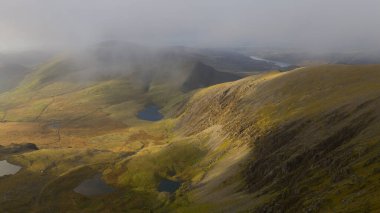 Snowdon Dağı 'nın ve Snowdonia Ulusal Parkı' nın çevresindeki dağlık arazilerin havadan görünüşü dramatik Galler tepeleri, engebeli arazi ve ikonik dağ manzarasını gözler önüne seriyor..