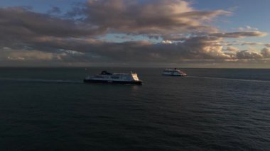 Dover, Kent County, İngiltere, 25 Ekim 2025: DFDS feribotunun gün batımında Dover Limanı 'na girişini gösteren hava aracı videosu, Fransa' dan Kent kıyı şeridi boyunca gelen çapraz-kanallı araç ve kamyon naklini gösteriyor..
