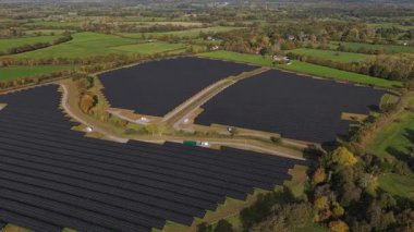 Yenilenebilir enerji üretimini ve fosil yakıtlardan sürdürülebilir, temiz enerji altyapısına geçişi vurgulayan, İngiltere kırsalındaki büyük güneş paneli alanlarının hava aracı videosu.