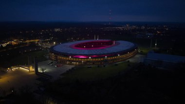 Geceleri Berlin Olimpiyat Stadyumu 'nun hava aracı görüntüsü mimariyi ve tarihi spor salonunu aydınlatıyor. Alman mirası, şehir manzarası ve dramatik gece şehir atmosferi sergileniyor..