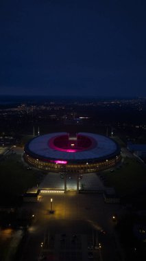 Geceleri Berlin Olimpiyat Stadyumu 'nun hava aracı görüntüsü mimariyi ve tarihi spor salonunu aydınlatıyor. Alman mirası, şehir manzarası ve dramatik gece şehir atmosferi sergileniyor..