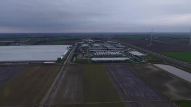 Hollanda, Middenmeer 'deki büyük ölçekli bir veri merkezinin hava aracı videosu, bulutlu bir günde büyük veri işleme altyapısını, bulut hesaplama tesislerini ve endüstriyel ölçekli teknolojiyi gösteriyor..