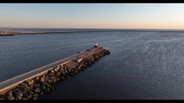 Hollanda 'daki IJmuiden limanının girişindeki Kuzey İskelesi' nin insansız hava aracı videosu. Gözetleme kulesi fenerini yakalıyor, gemileri geçiyor ve Kuzey Denizi üzerinde dramatik gün batımı manzarası var..