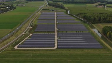 Hollanda, Puiflijk yakınlarındaki Zevent Güneş Parkı 'nın insansız hava aracı videosu büyük ölçekli güneş panelleri, yenilenebilir enerji üretimi ve Hollanda haneleri için sürdürülebilir enerji üretimini gösteriyor..