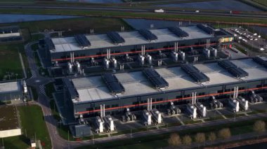 Hollanda, Middenmeer 'de bulunan ve yedek güç, soğutma sistemleri ve bulut ve yapay zeka hizmetlerini destekleyen yüksek performanslı bilgisayar altyapısını gösteren büyük bir veri merkezinin insansız hava aracı videosu..
