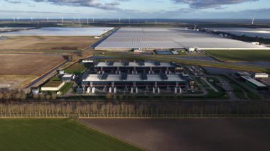 Hollanda, Middenmeer 'de bulunan ve yedek güç, soğutma sistemleri ve bulut ve yapay zeka hizmetlerini destekleyen yüksek performanslı bilgisayar altyapısını gösteren büyük bir veri merkezinin insansız hava aracı videosu..