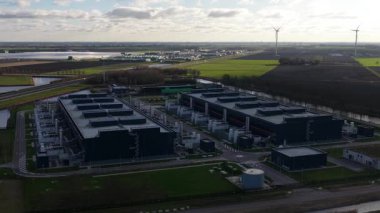 Hollanda, Middenmeer 'de bulunan ve yedek güç, soğutma sistemleri ve bulut ve yapay zeka hizmetlerini destekleyen yüksek performanslı bilgisayar altyapısını gösteren büyük bir veri merkezinin insansız hava aracı videosu..