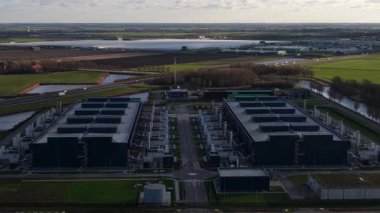 Hollands Kroon 'daki yüksek ölçekli veri merkezlerinin hava aracı videosu, modern dijital ekonomileri şekillendiren büyük ölçekli bilgisayar, bulut altyapısı, dijital depolama ve enerji yoğunluklu tesisleri gösteriyor..