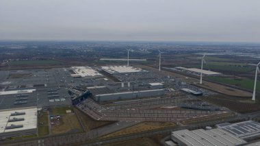 Leipzig 'deki büyük bir otomobil üretim tesisinin hava görüntüsü, otomotiv üretim salonları ve sanayi altyapısını bulutlu bir gökyüzünün altında gösteriyor..