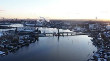 Zaandijk, Koog aan de Zaan ve Coenbrug köprüsünün güneşli bir günde Hollanda nehir kenarındaki kasaba, mimari ve manzaraları gösteren kış drone videosu..