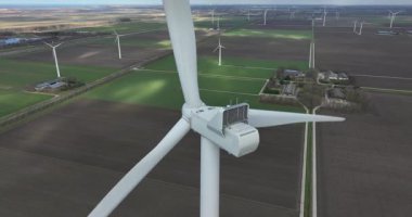 Rüzgar türbinleri, tarımsal alanda dönen pervaneler, düz yeşil alanlar. Hava aracı görüntüyü kapat.