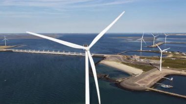 Büyük bir rüzgar türbininin kıyı rüzgâr çiftliği ve arka planda sürdürülebilir enerji üretimi bariyeri ile yavaşça dönen havadan görünüşü