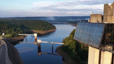 Gileppe Barajı 'nı ve panoramik gözlem kulesini görüntüleyen muhteşem hava görüntüleri, yemyeşil bir vadide, yemyeşil bir yaz gündoğumu sırasında bulunan rezervuarın sakin suyunu yansıtıyor.