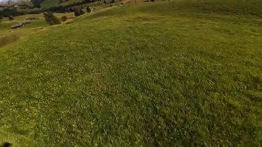 Fpv İHA uçuşu canlı yeşil bir otlağın üzerinde süzülüyor, güneşli bir günde güneşli bir dağ grubuyla Alpe di Siusi 'nin büyüleyici alp manzarasını gözler önüne seriyor