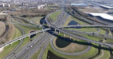 Birden fazla üst geçidi ve rampası olan karmaşık bir otoyol kesişiminin hava perspektifi. Çağdaş altyapı boyunca ilerleyen karmaşık yol ağını ve sürekli trafik akışını gösteriyor