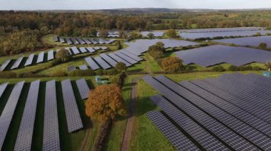 İnsansız hava aracı görüntüsü, fotovoltaik panellerle dolu geniş bir güneş çiftliğinin üzerinde uçuyor güzel bir kırsal alanda temiz elektrik üretiyor, yenilenebilir enerji ve sürdürülebilir teknolojiyi destekliyor.