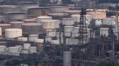 Geniş bir petrol rafinerisi, sayısız büyük depolama tankları, karmaşık borular ve yüksek yapılar içeren uçsuz bucaksız sanayi arazisi, petrol ve enerji üretiminin ölçeğini vurguluyor.