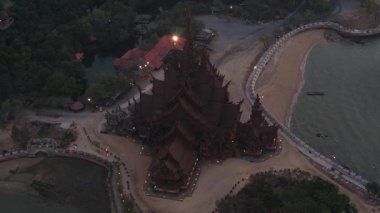 Pattaya, Tayland 'daki görkemli ahşap bina alacakaranlık gökyüzüne ve kıyı şeridindeki sakin denize karşı aydınlandı.