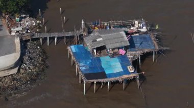 Kırsal kesimdeki ahşap balıkçıların yüksek açılı manzarası bir nehrin çamurlu sularının üzerine inşa edilmiş bir ev, Asya 'daki bir sahil bölgesinde geleneksel ve yoksul bir yaşam biçimini gösteriyor.