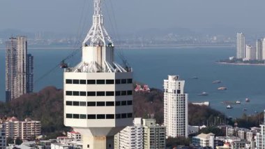 Kule tepesinde dönen panoramik bir restoran şehrin, sahil şeridinin ve suda yüzen teknelerin olduğu Tayland körfezinin çarpıcı bir hava manzarası sunuyor.