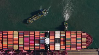 Büyük bir konteyner gemisinin ticari bir limanda manevra ve rıhtıma yanaşması, küçük römorkörlerin yardımıyla küresel deniz lojistik ve ticaret ölçeğini gözler önüne seriyor.