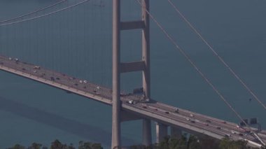 Tsing ma Köprüsü 'nün hava perspektifi, önemli bir mimari dönüm noktası, aşağıdaki sakin mavi su üzerinde geniş yol ağında sürekli araç trafiğinin aktığını gösteriyor.