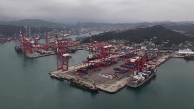 Keelung, Ren ai Bölgesi, Tayvan, 23 Şubat 2026: Tayvan 'ın hareketli liman limanının geniş bir hava perspektifi, bulutlu bir günde endüstriyel nakliye terminalinde kırmızı kanat vinçleri tarafından yüklenen büyük konteyner gemileri