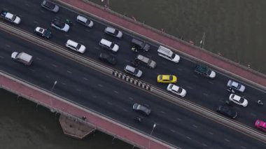 Yüksek açı perspektifi, yoğun bir araba, kamyon ve motosiklet akışının nehrin üzerindeki çok şeritli bir köprüde gidip gelişini gösteriyor.