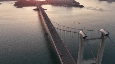Tsing ma süspansiyon köprüsünün görkemli hava manzarası. Güzel ve sinematik bir günbatımında trafik suyun üzerinde akıyor. Lantau adasını Hong Kong şehrine bağlıyor.
