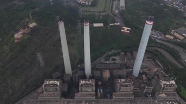 Yeşil bir vadiye kurulmuş bir termik santralin dramatik hava perspektifi devasa endüstriyel altyapısını ve engebeli araziye karşı önemli bacalarını gözler önüne seriyor.