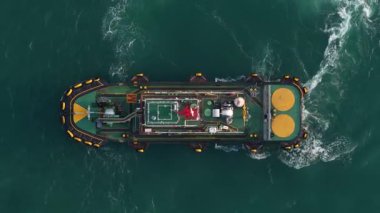 Endüstriyel petrol ve kimyasal tanker gemisi sakin yeşil okyanus sularında yüzüyor. Havadan aşağıya doğru olan görüntü, geminin deniz yüzeyinde beyaz bir iz bıraktığını gösteriyor.