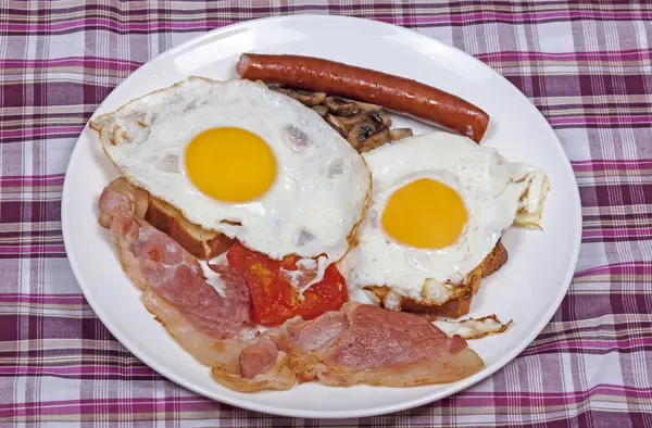 Petit déjeuner aux œufs et au bacon sur nappe à carreaux — Photo